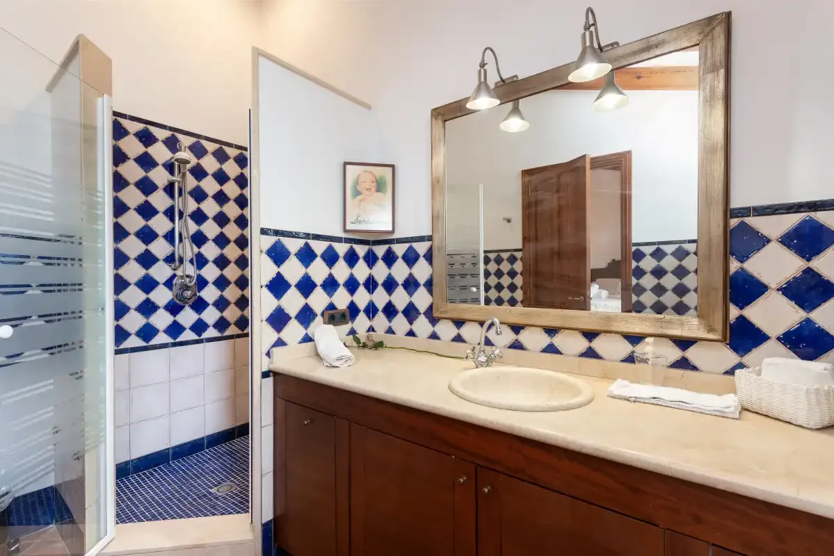 Un baño alicatado con ducha, lavabo y un gran espejo de pared.