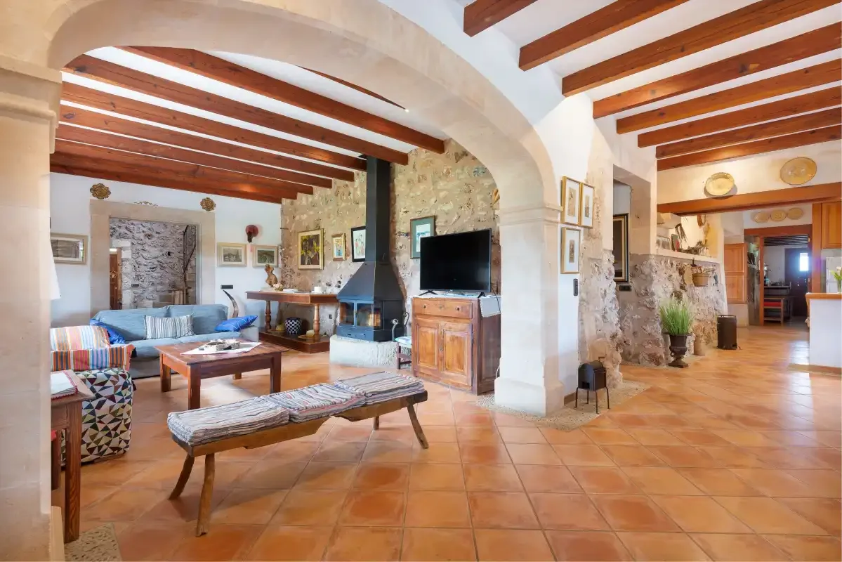 Una sala de estar amplia con asientos, una chimenea y vigas de techo expuestas.
