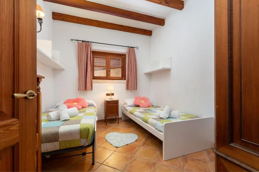 Un dormitorio con dos camas, una ventana pequeña y vigas de madera expuestas en el techo.