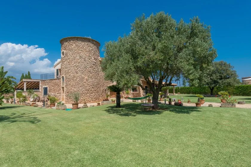 Un edificio de piedra está junto a un árbol grande en un césped.