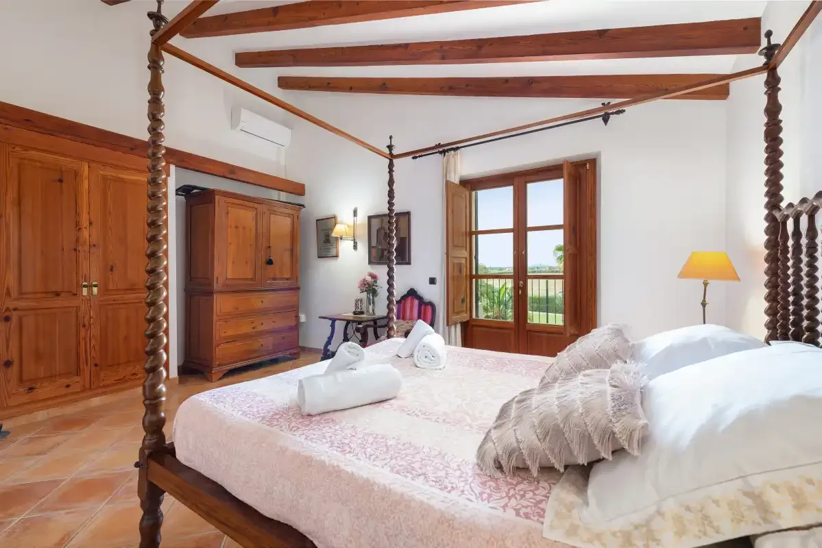 Un dormitorio con una cama grande, muebles de madera y una ventana con vistas a la vegetación.