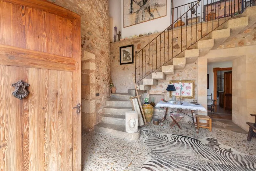 Un interior rústico de piedra con una escalera sobre un pequeño comedor.