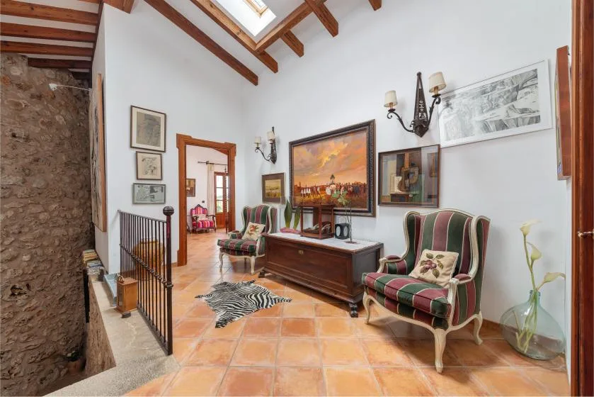 Una sala luminosa con sillones estampados y un cuadro grande enmarcado.