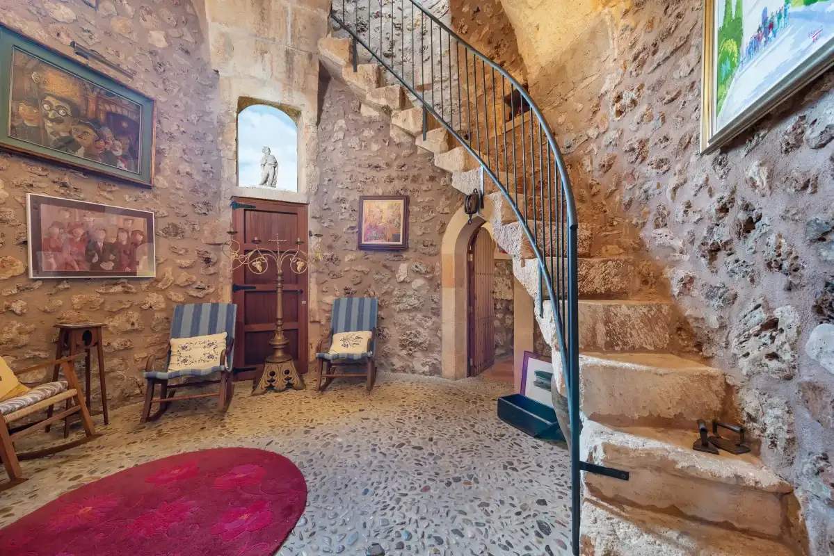 Un interior de paredes de piedra con una escalera curva y asientos.