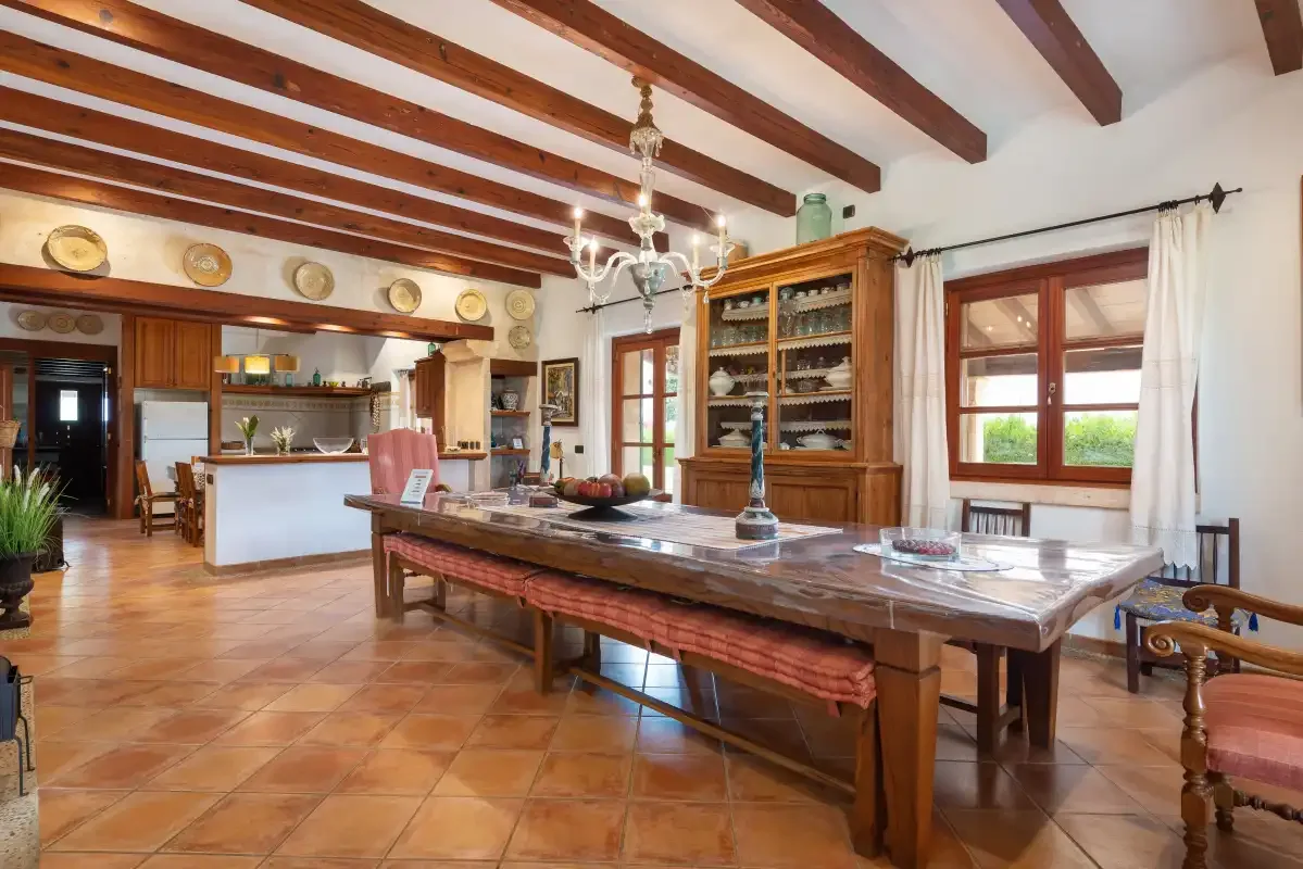 Un amplio comedor con una larga mesa de madera y una cocina contigua.