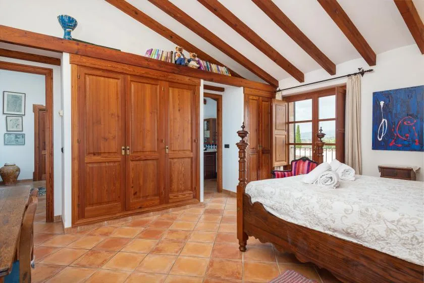 Un dormitorio con una cama de madera, ropa de cama blanca y un armario grande de madera.