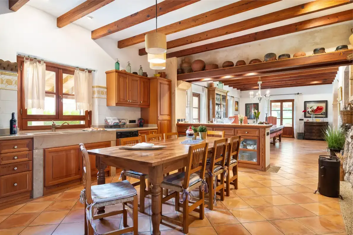 Una amplia cocina y zona de comedor con vigas de madera y una mesa larga.