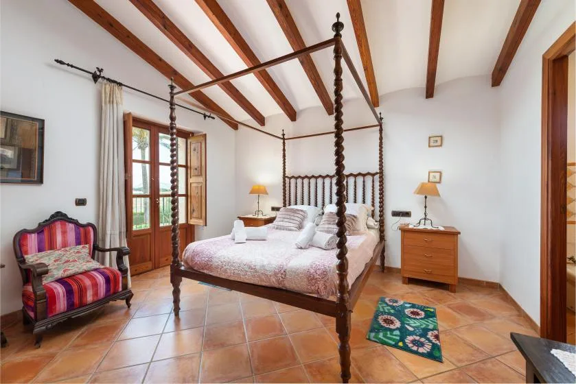 Un dormitorio con una cama con dosel y un sillón tapizado de colores.