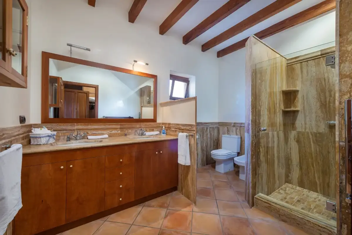 Un baño con un lavabo largo, un espejo y una ducha de vidrio.