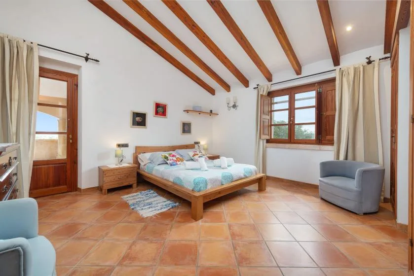 Un dormitorio con una cama de madera, ropa de cama colorida y vigas expuestas.