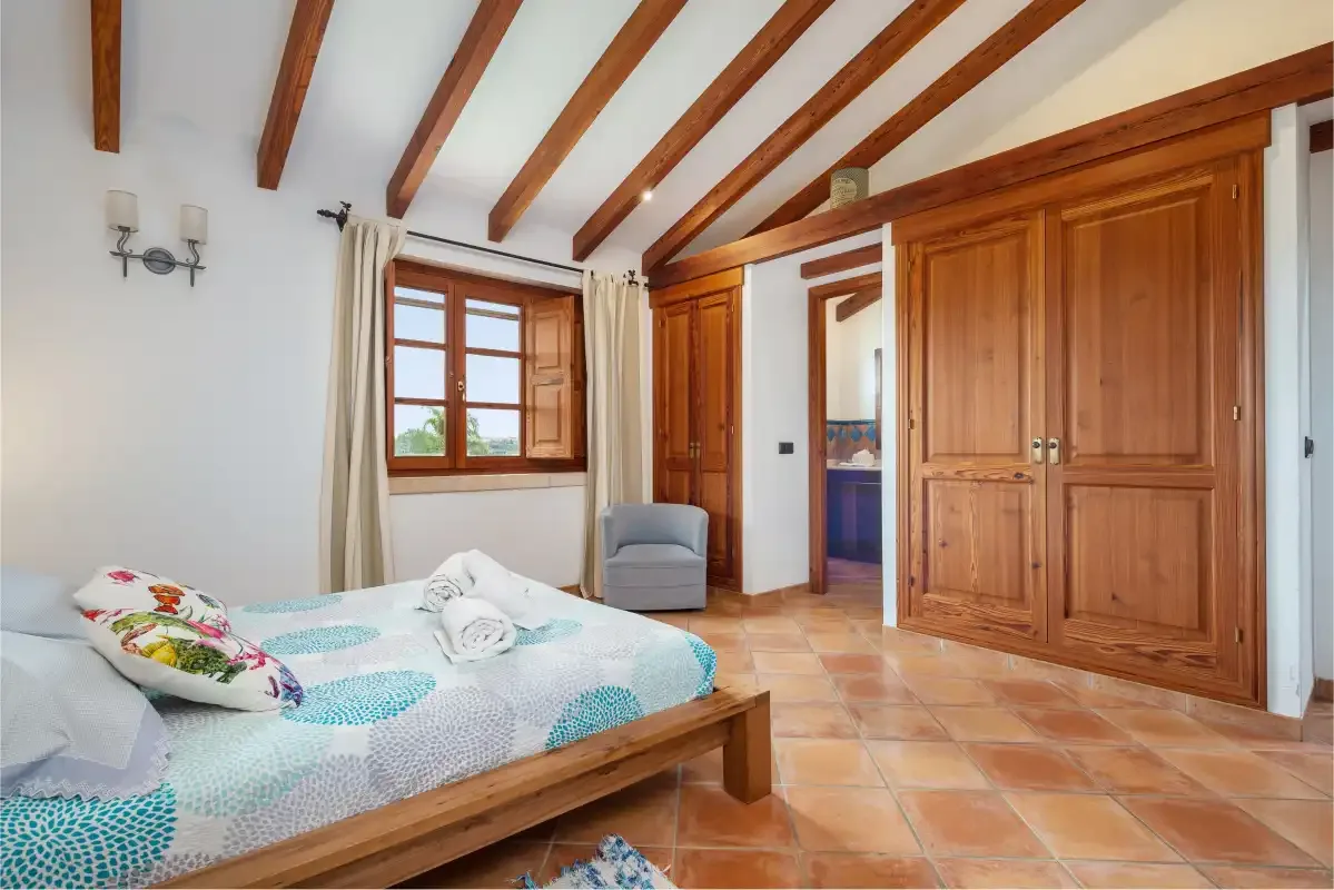 Un dormitorio con una cama de madera, una ventana y armarios empotrados.