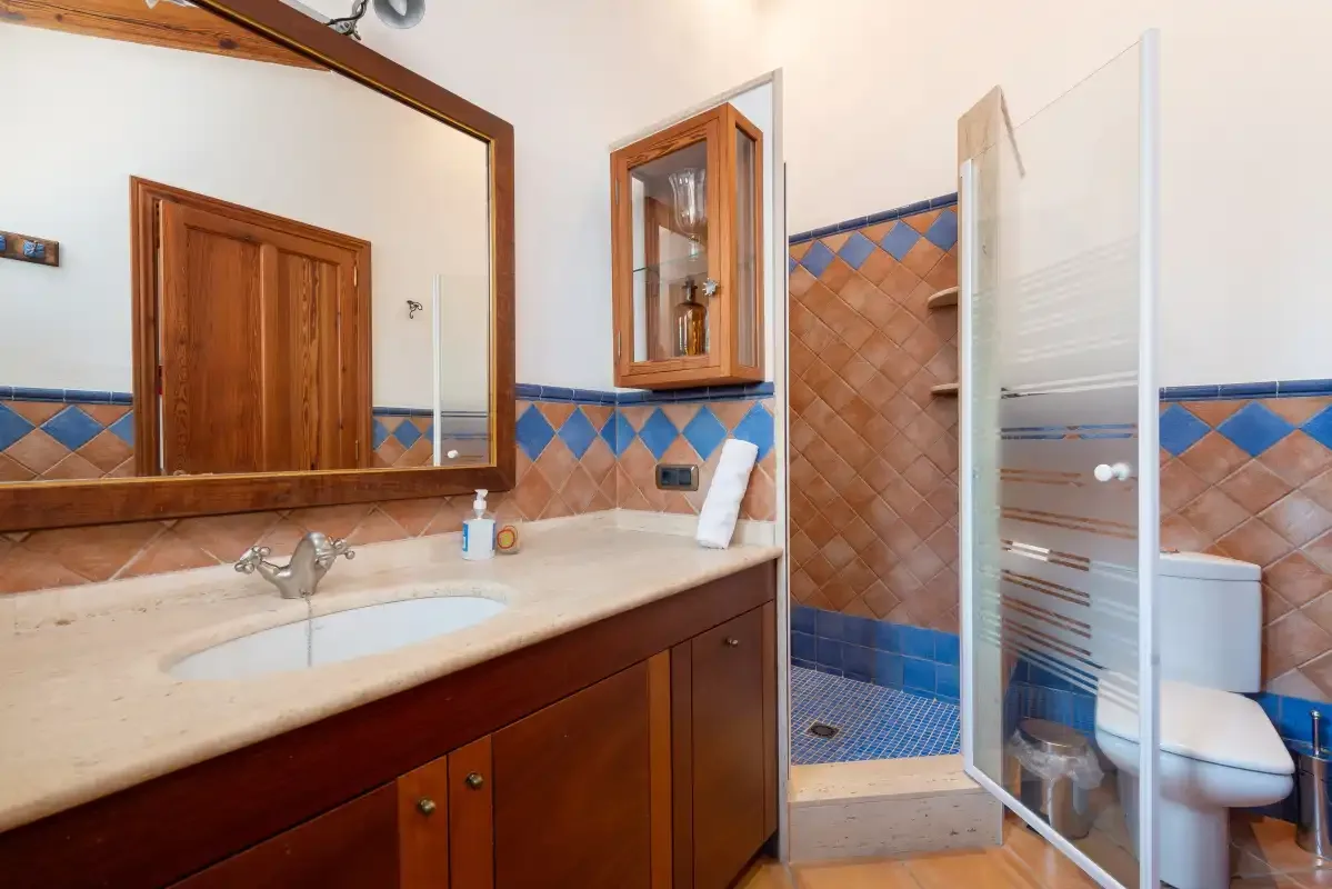 Un baño con una larga encimera con lavabo y una mampara de ducha de vidrio.