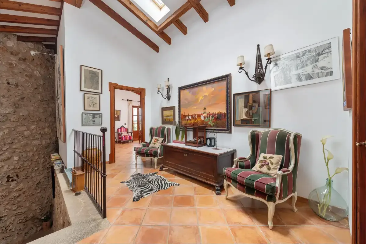 Una sala de estar con asientos tapizados y un arcón de madera bajo un cuadro grande.