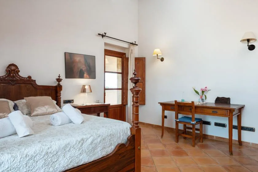 Un dormitorio con una cama de madera y un escritorio junto a la ventana.