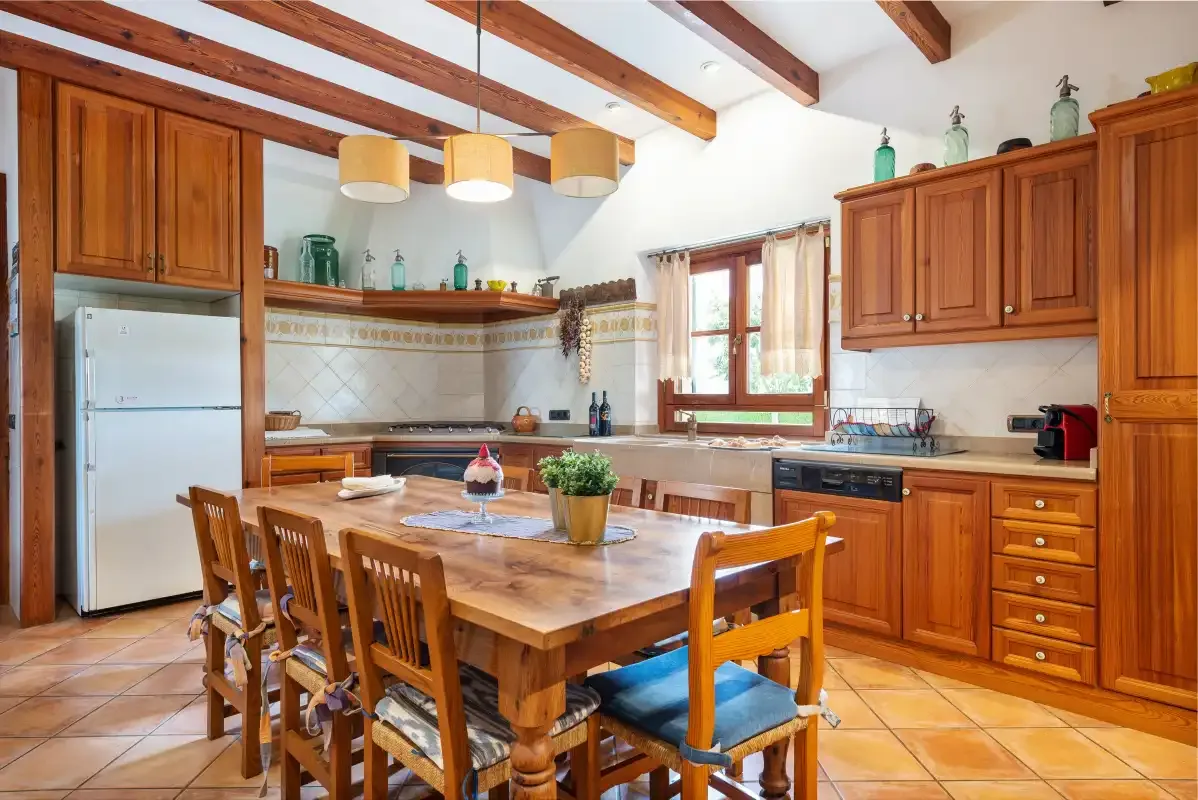 Una cocina rústica con armarios de madera y una mesa de comedor bajo vigas vistas.