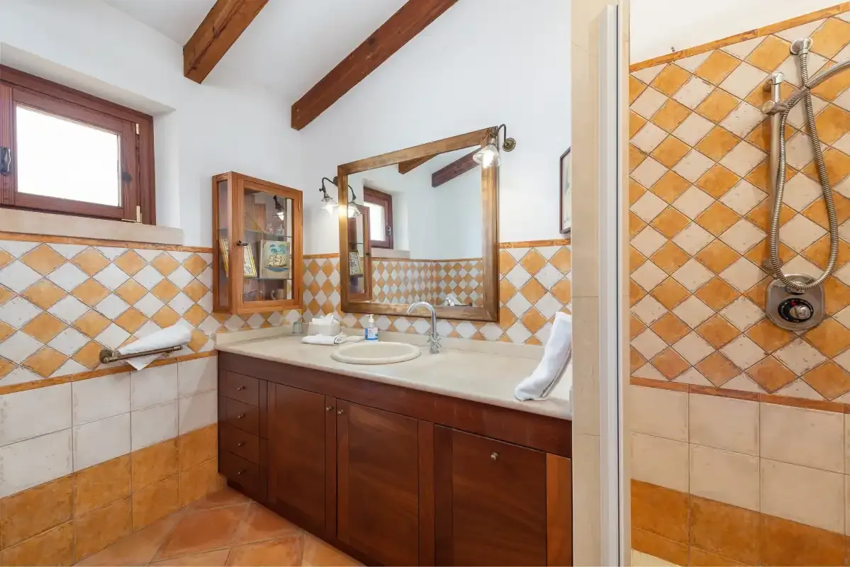 Un baño alicatado con lavabo, espejo y ducha.