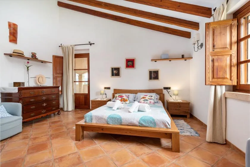 Un dormitorio con una cama de madera, mesitas de noche y vigas vistas en el techo.