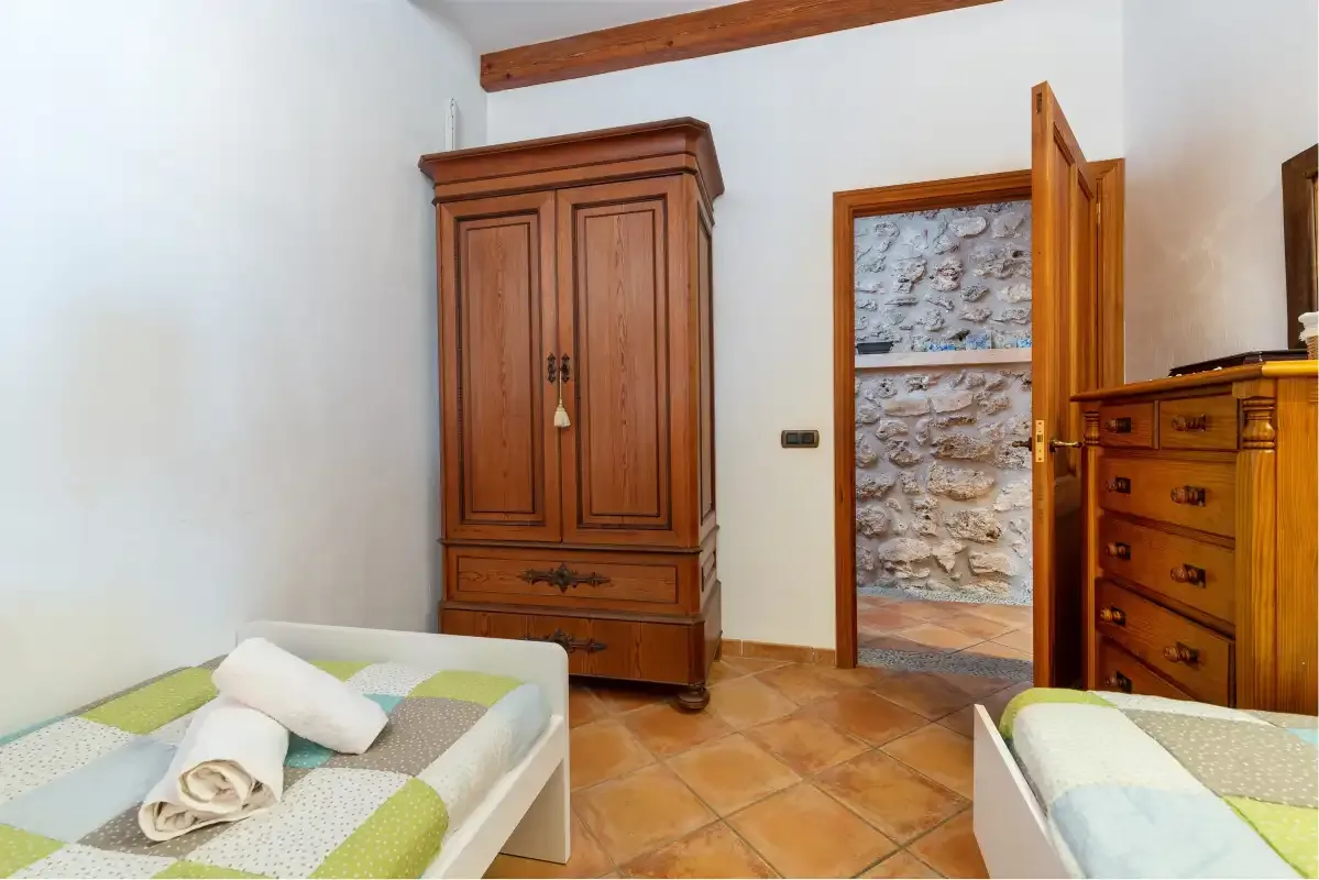 Un dormitorio con dos camas individuales, muebles de madera y una puerta abierta.
