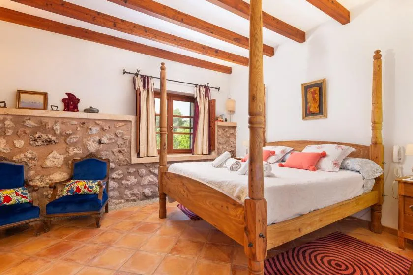 Un dormitorio con una cama con postes de madera y vigas vistas en el techo.