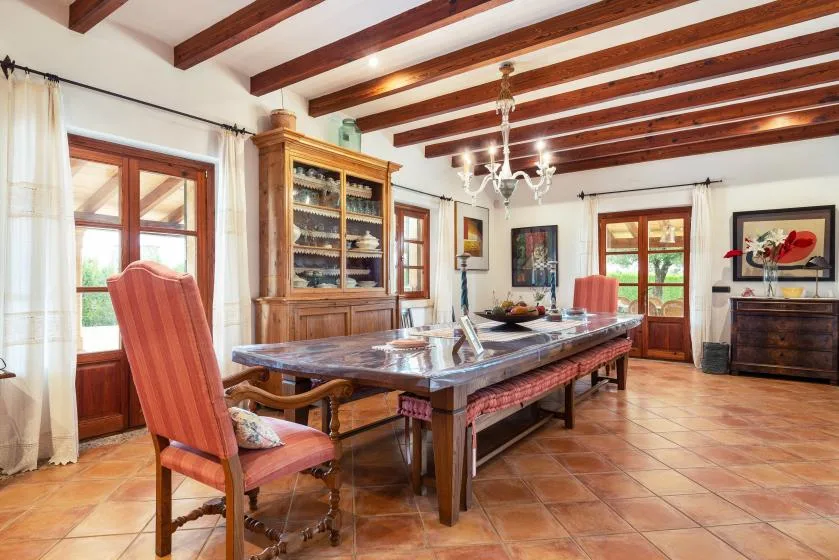 Un comedor con una mesa larga, asientos de madera y vigas expuestas en el techo.