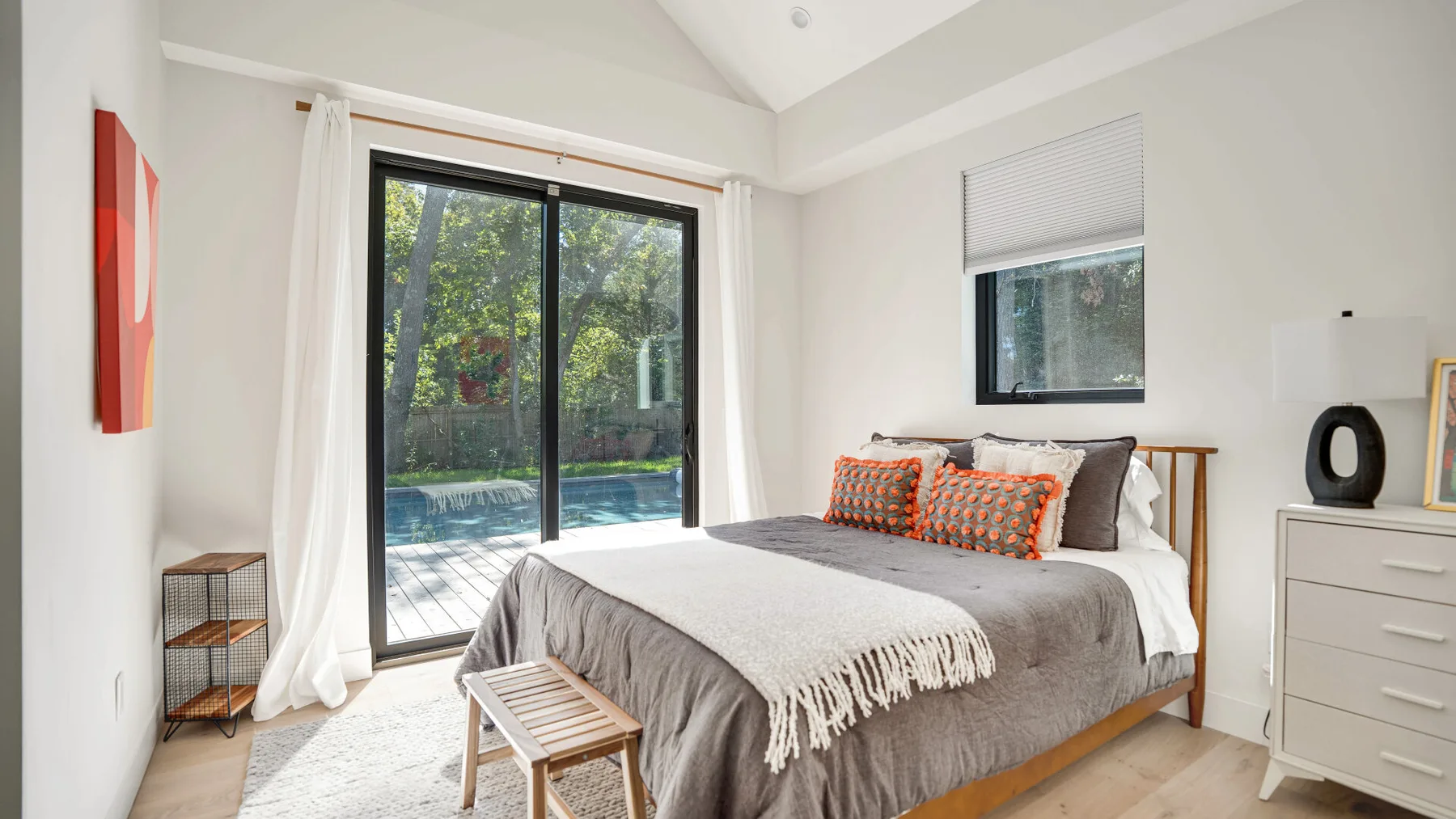 Un dormitorio luminoso con una cama grande junto a puertas de vidrio que dan a un patio.
