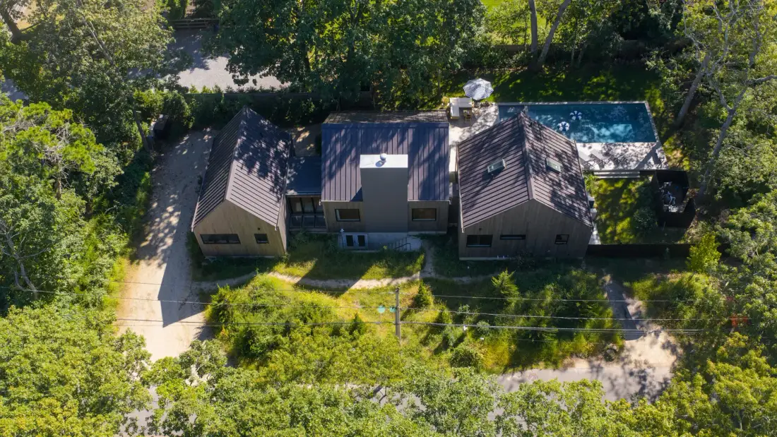 Vista aérea de una casa rodeada de árboles, con una piscina a un lado.