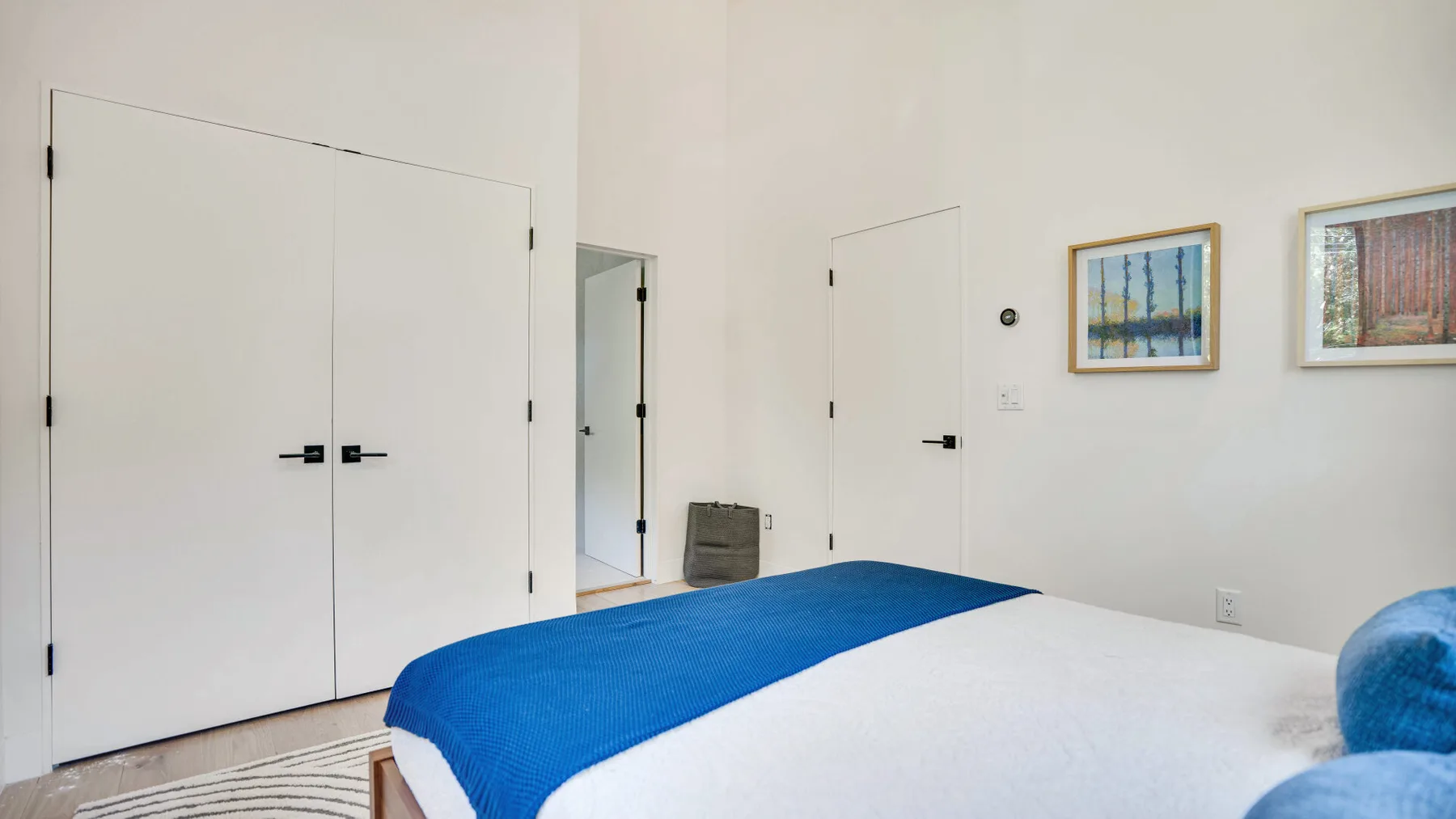 Un dormitorio con una cama tendida y cuadros enmarcados en la pared.