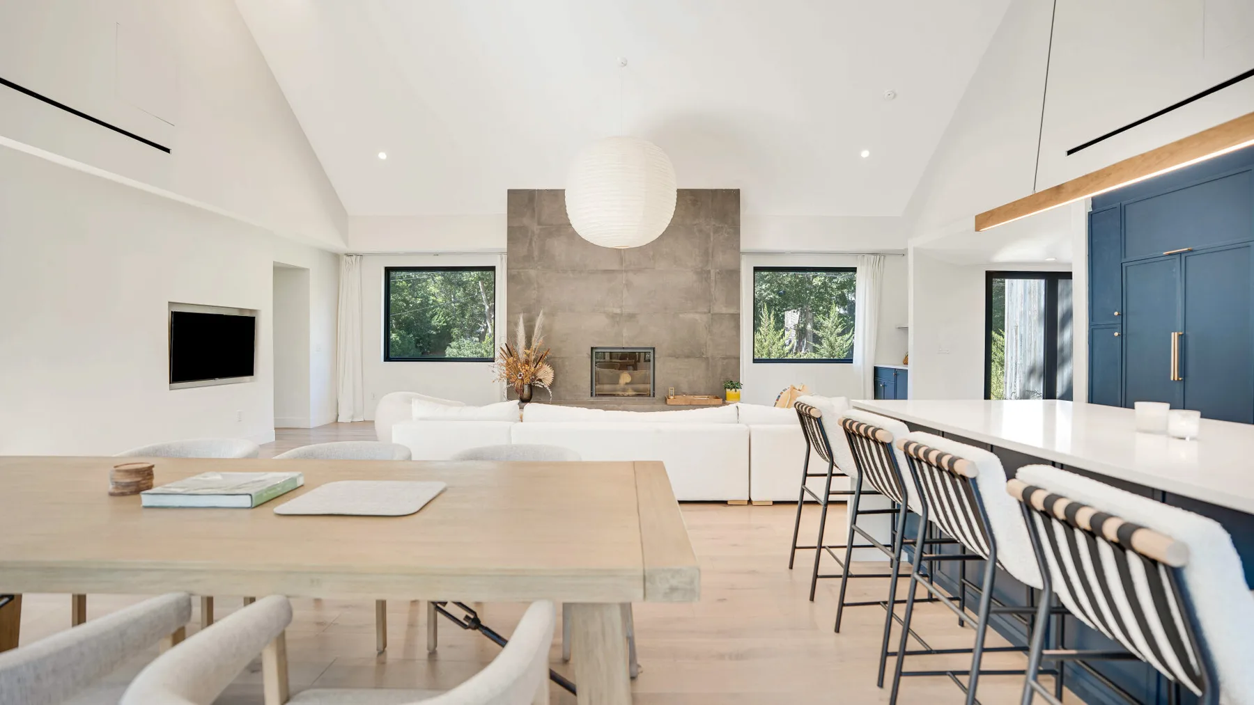 Una luminosa sala de estar y comedor con chimenea y una mesa larga.