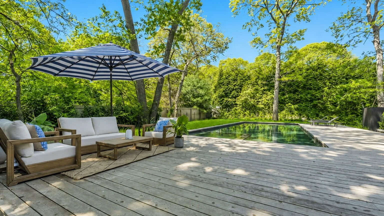Una terraza exterior con asientos y una sombrilla junto a una piscina.