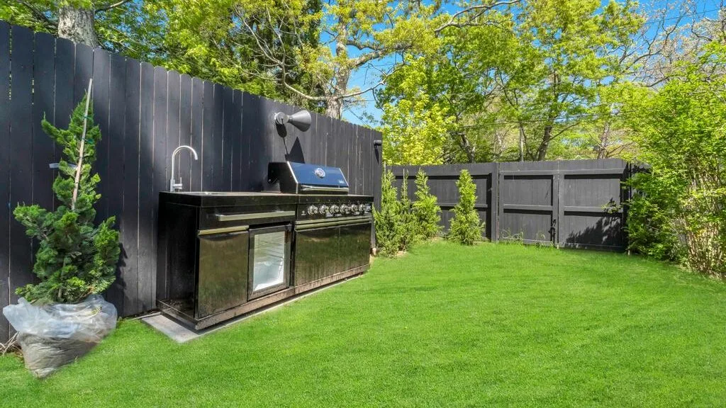 Una zona de cocina al aire libre con una parrilla junto al césped.