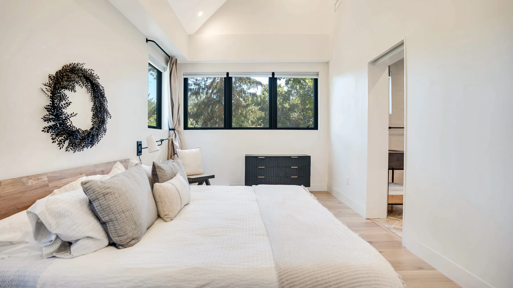 Un dormitorio luminoso con una cama grande bajo una ventana amplia.
