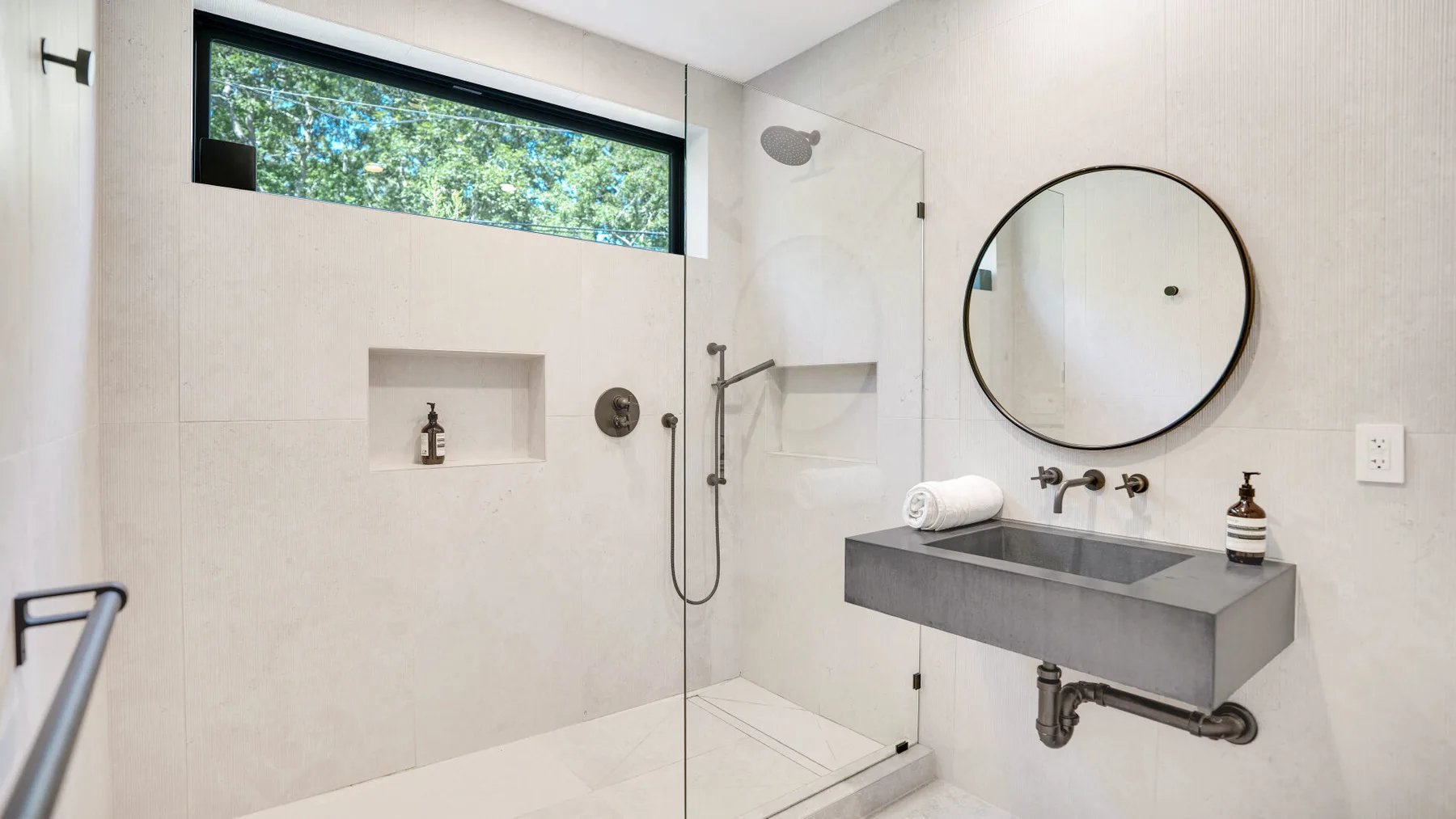 Un baño luminoso con ducha y lavabo suspendido.