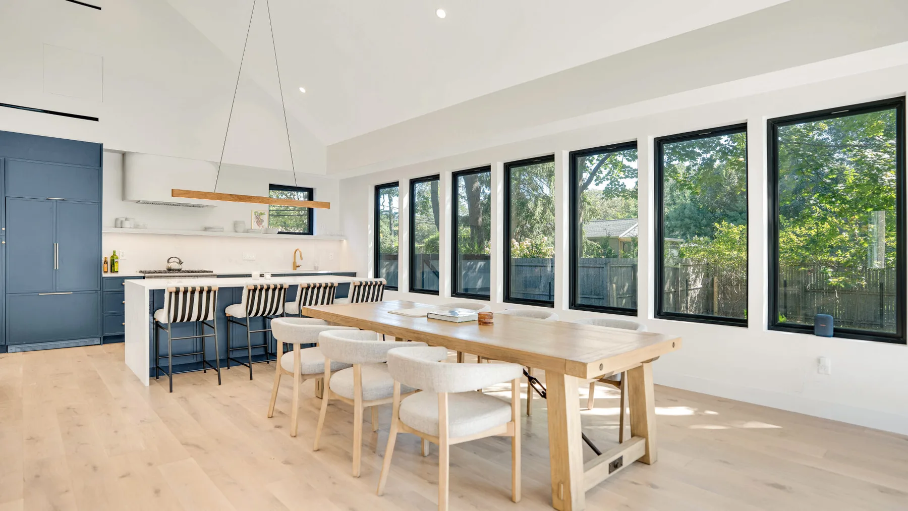Un comedor luminoso con una mesa larga junto a grandes ventanas.
