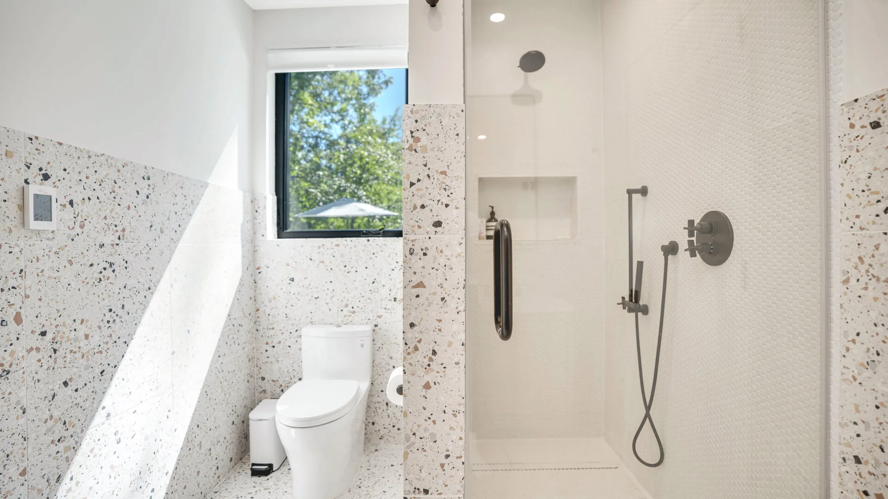 Un baño luminoso con un inodoro y una zona de ducha de vidrio.