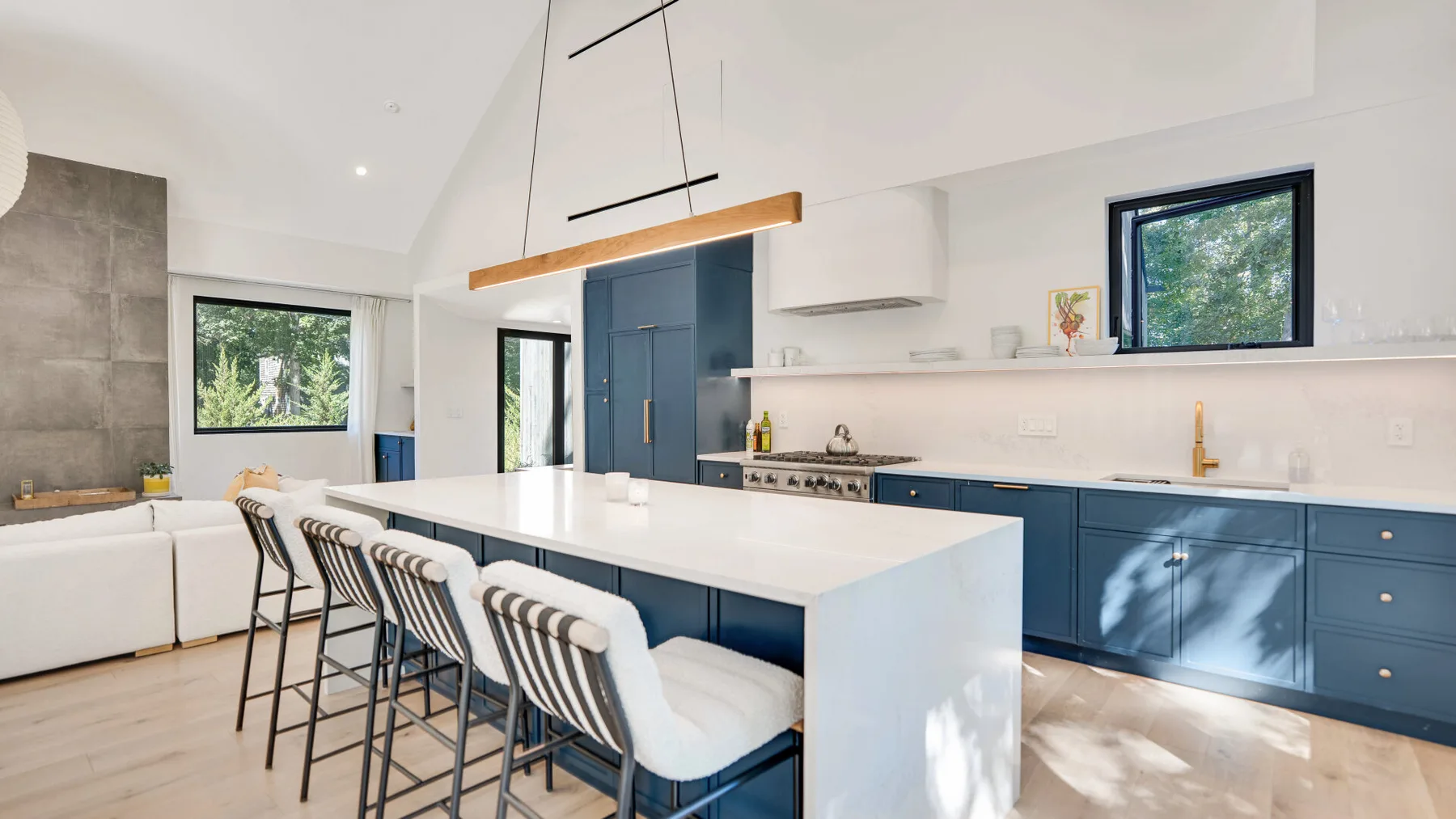 Una cocina moderna y luminosa con una isla grande y gabinetes azules.
