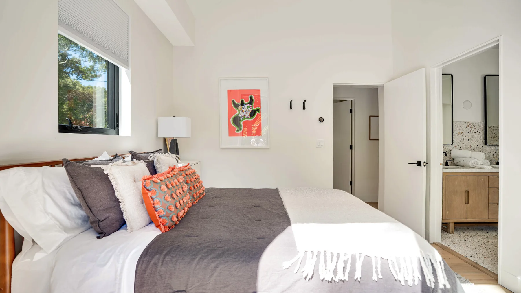 Un dormitorio luminoso con una cama grande, arte colorido y una ventana.