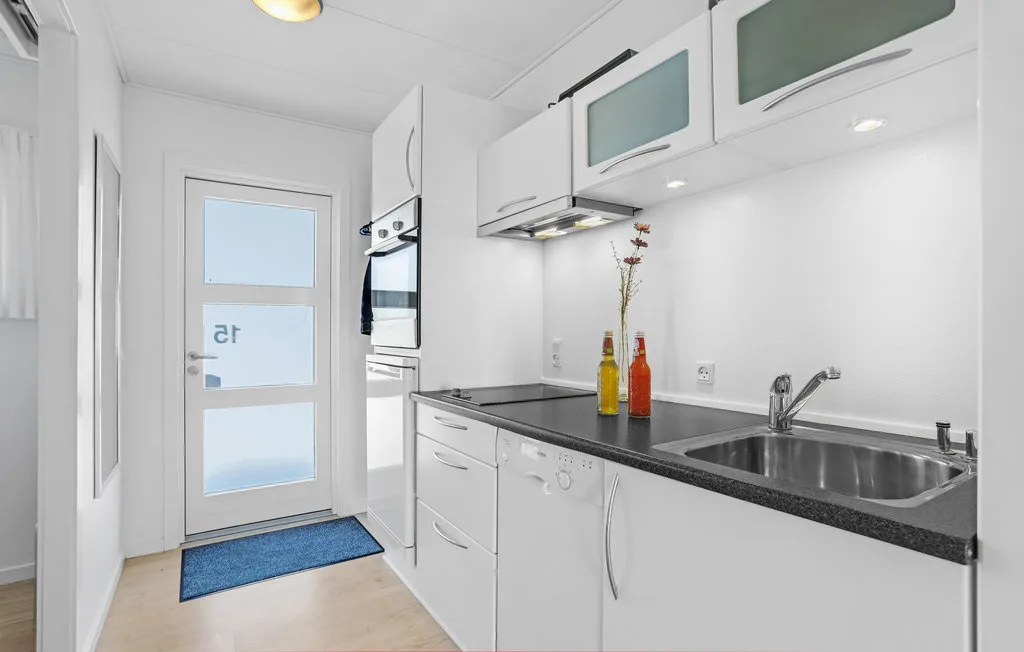 A bright white kitchen with a countertop, sink, and built-in appliances.
