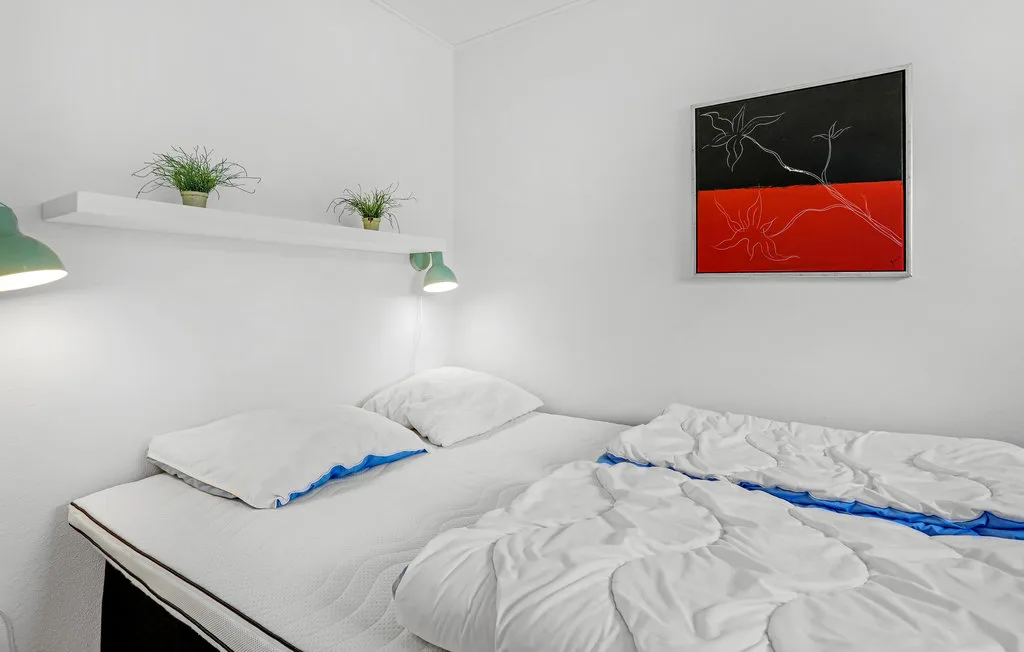 A bedroom with two beds dressed in white bedding and a framed wall print.