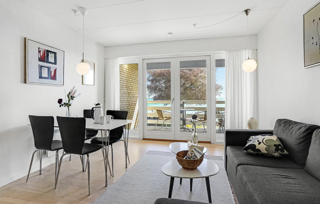 A bright living and dining area opens onto a balcony through glass doors.