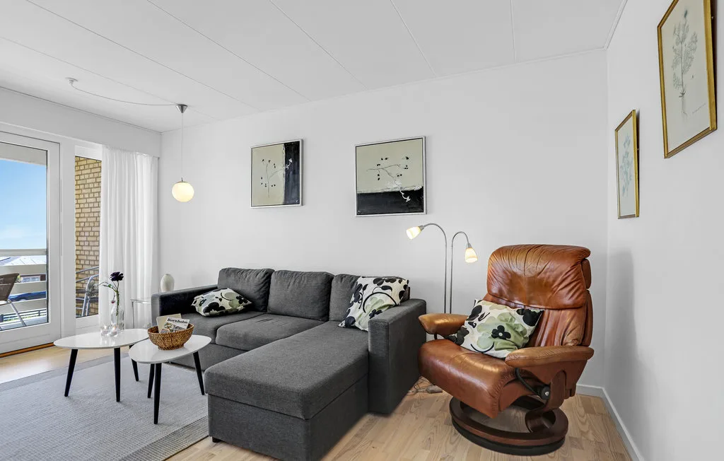 Sala de estar con un sofá seccional gris, un sillón reclinable marrón y cuadros.