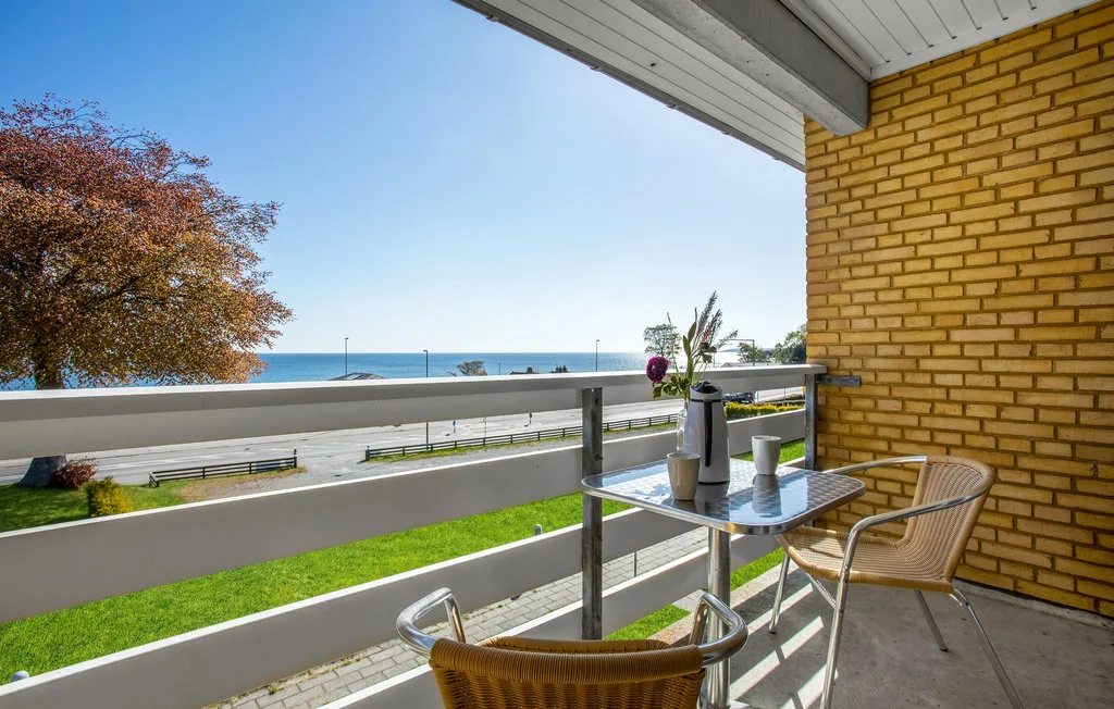 A balcony seating area overlooks the ocean, with a small table beside the railing.