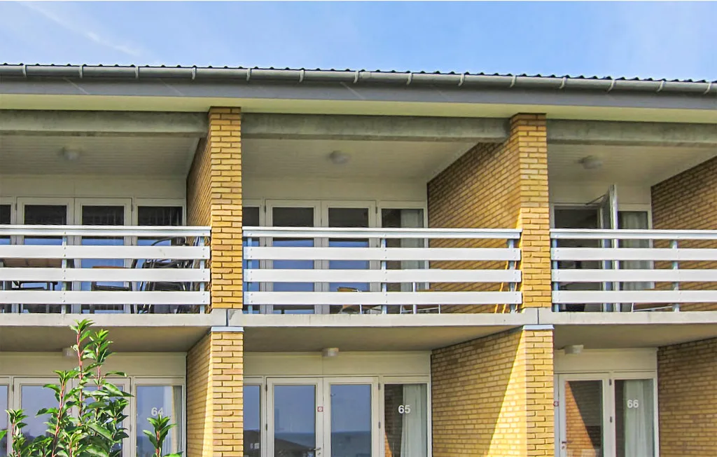 A two-story building facade has brick columns, balconies, and glass doors.