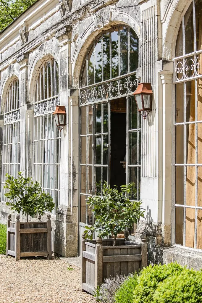 Building façade with arched windows and potted shrubs