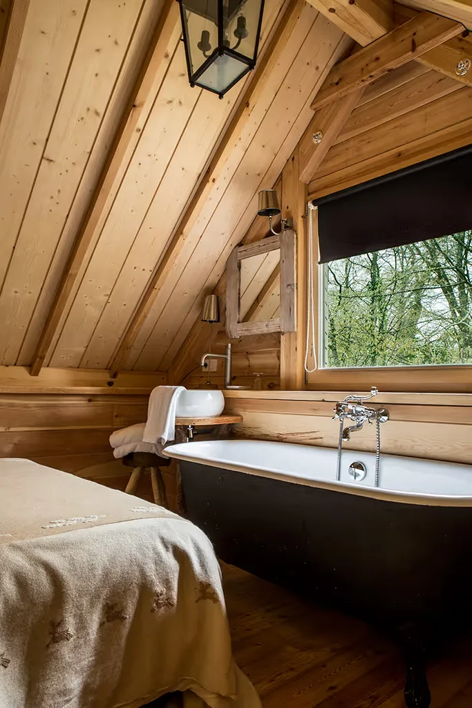 Bathroom with a black bathtub, white basin and garden view