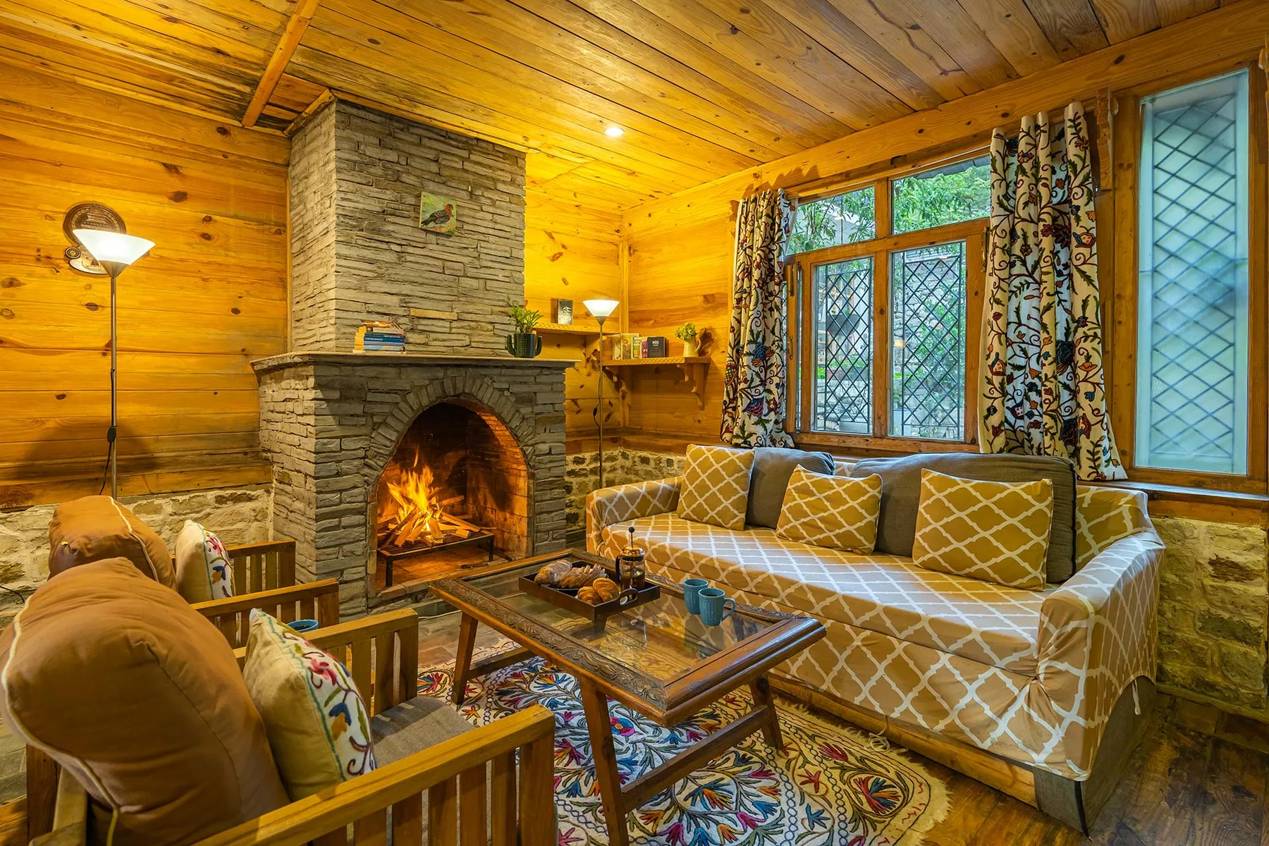 Una sala con paneles de madera presenta una chimenea de piedra y asientos estampados.