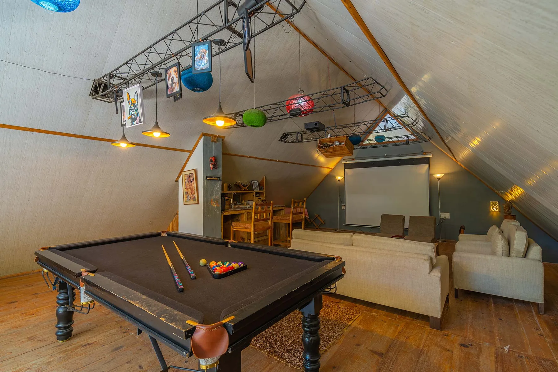 Una sala de juegos con una mesa de billar, asientos y una pantalla de proyección.
