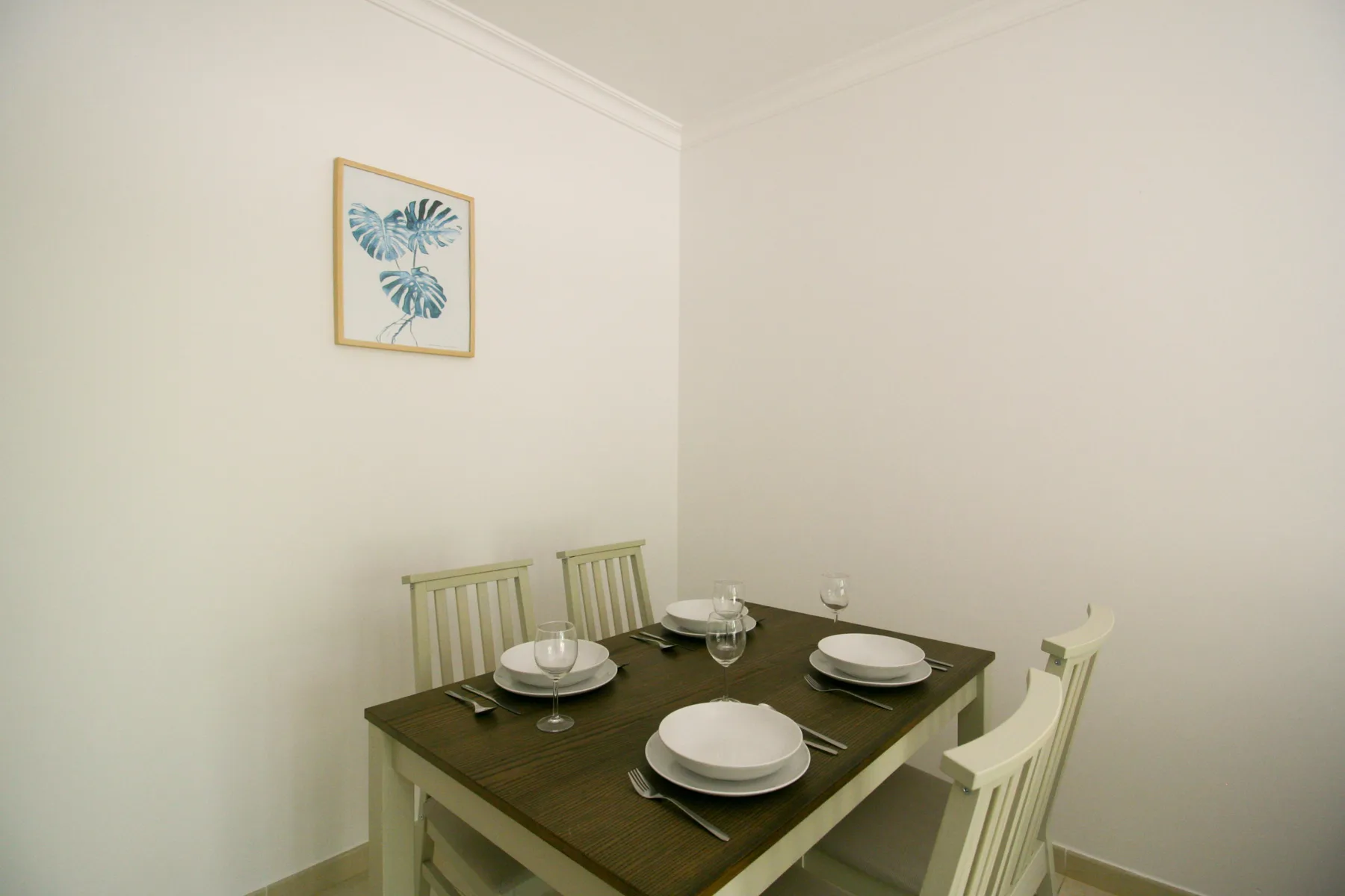 Comedor con mesa oscura, sillas y una lámina botánica enmarcada.