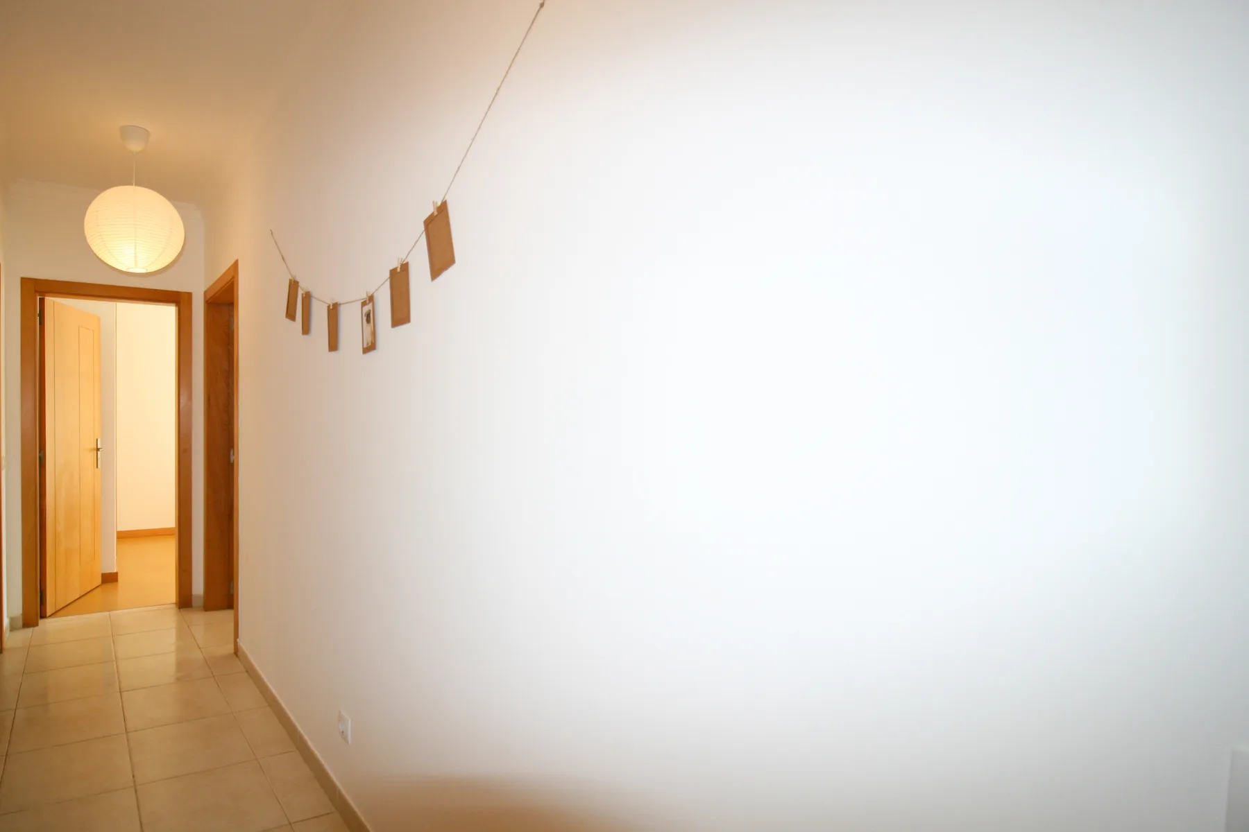 Un pasillo luminoso con suelo de baldosas y una decoración colgante de papel.