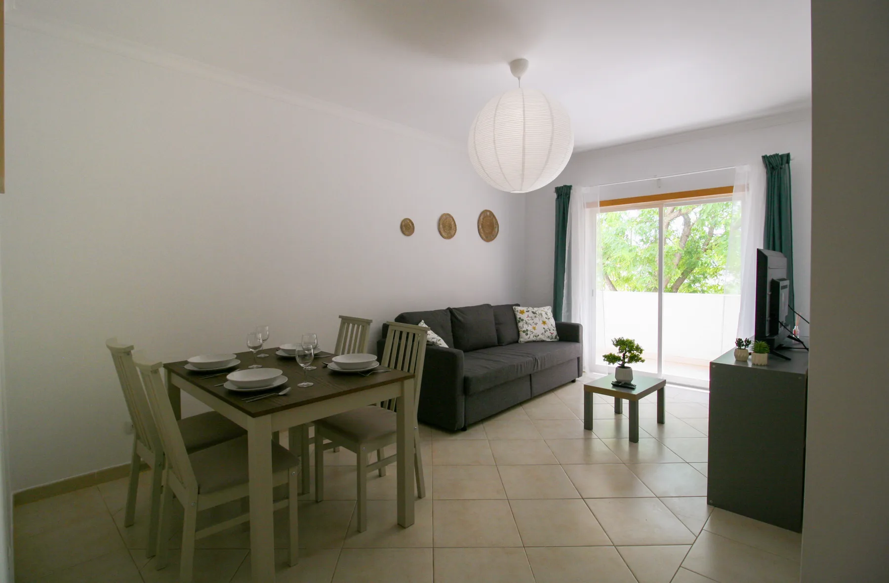 Sala de estar y comedor con la mesa puesta, un sofá y una ventana luminosa.