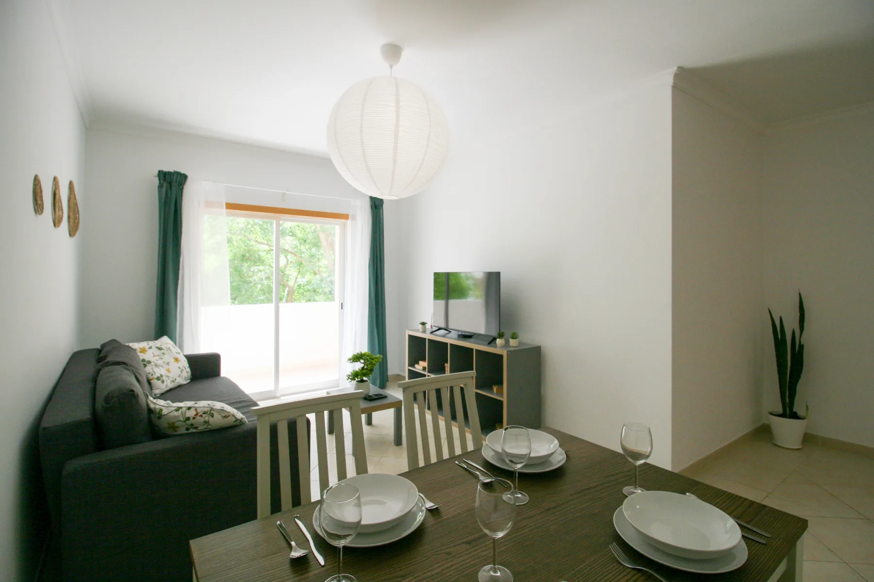 Sala de estar y comedor con un sofá oscuro junto a una ventana luminosa.